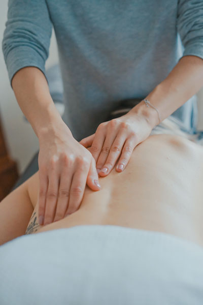Deep tissue massage - Woman giving a massage to a woman lying down on the table, covered with white towel