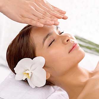 Reiki Healing - A woman with white flower in her hair lying down and getting reiki healing.
